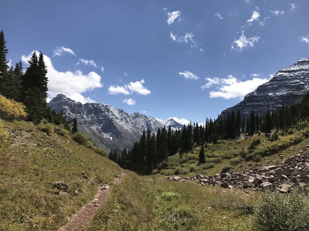 A trail climbing through a valley toward rugged peaks
